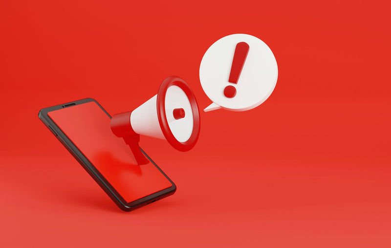 A 3D rendered graphic showing a megaphone emerging from a smartphone screen next to an exclamation mark speech bubble, set against a solid red background.