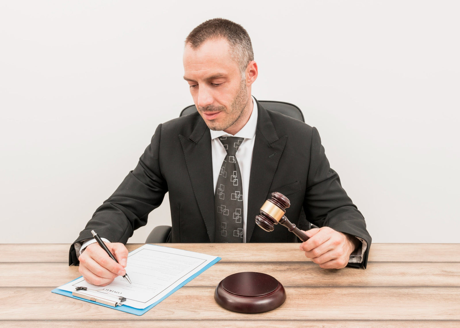 A judge or legal official holding a wooden gavel while filling out agreement papers on a clipboard, representing confession of judgment reforms and commercial finance legal agreements.