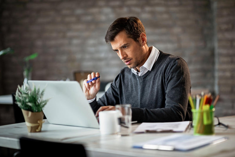 A commercial finance sales rep working on a laptop at his desk, managing outbound SMS campaigns and tracking lead responses in real time.