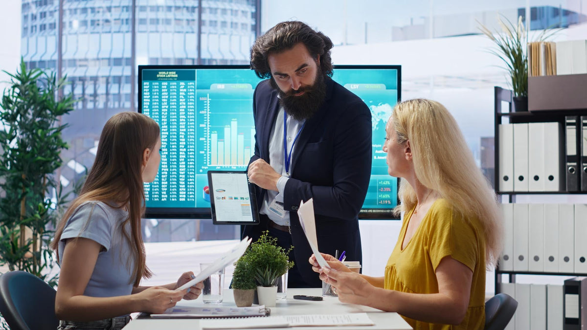 Commercial finance ISO sales director pointing at a tablet screen while reviewing conversion benchmarks and dialer metrics with brokers.