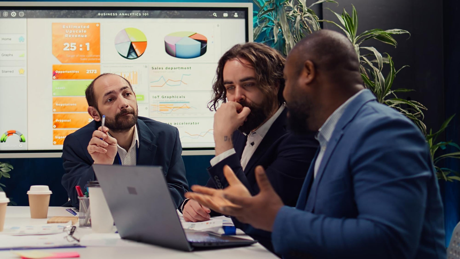 Corporate team of small business loan lenders discussing high-intent business funding data, market analytics dashboards, and merchant cash advance conversion metrics around a laptop
