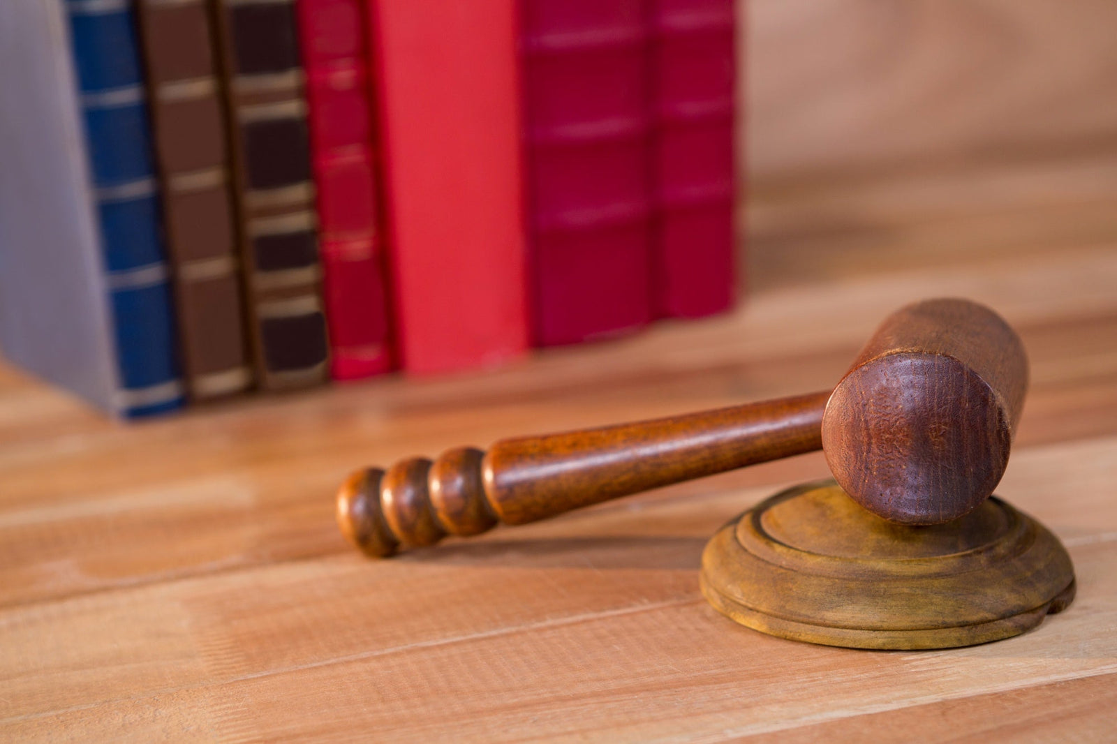 A close-up of a wooden judge's gavel on a desk with law books blurred in the background, representing state-by-state merchant cash advance disclosure regulations and legal compliance trackers.